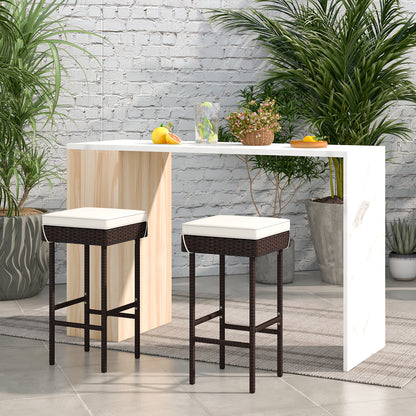 Set of two rattan outdoor patio barstools with footrests and soft cushions, ideal for backyard or balcony seating.