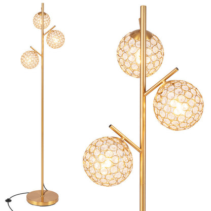 Three-globe floor lamp with brass finish and a mid-century modern accent chair in a stylish living room setting.