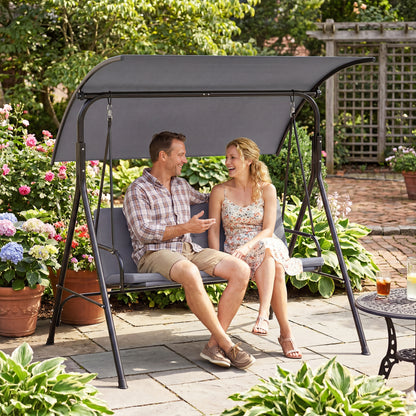 Beige patio swing chair with adjustable canopy, removable cushion, and metal stand for outdoor porch relaxation.